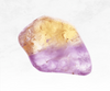 An alluring image of an ametrine crystal chunk, featuring a mesmerizing blend of vibrant purple and golden yellow hues. The crystal's distinct color division creates a captivating contrast, showcasing the unique combination of amethyst and citrine in a single stone. Its polished surface reflects light, illuminating the inherent beauty and harmony of this rare gemstone.
