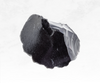 A striking image of a black obsidian crystal chunk, exhibiting a glossy, opaque black color. The crystal's surface appears smooth and reflective, emanating a sense of grounding and protection, while also hinting at hidden depths and mysteries.