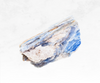 A mesmerizing image of a blue kyanite crystal chunk, showcasing a rich blue color with striations and a smooth texture. The crystal's unique blade-like formations evoke a sense of clarity, communication, and connection.