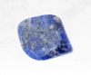 An image of a sodalite crystal chunk, displaying a captivating deep blue color interspersed with veins of white. The stone's polished surface highlights its vibrant beauty, promoting intuition, communication, and inner harmony.
